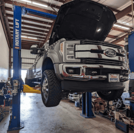 Ford truck on a hydraulic lift at Destination Autoworks for repair and maintenance.