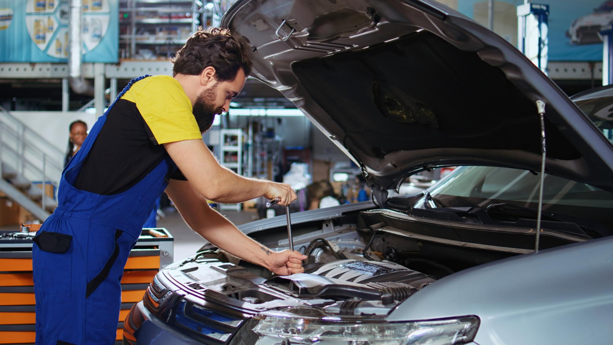 Technician inspecting car engine during tire service at Dettwiler Brothers Repair.