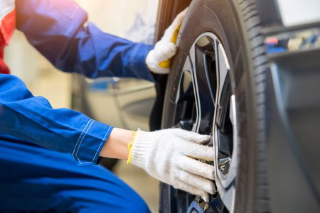 Technician performing wheel alignment on a vehicle at Dettwiler Brothers Repair.