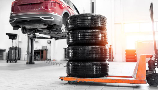Car tire stacking and vehicle lift at Dettwiler Brothers Auto Repair shop.