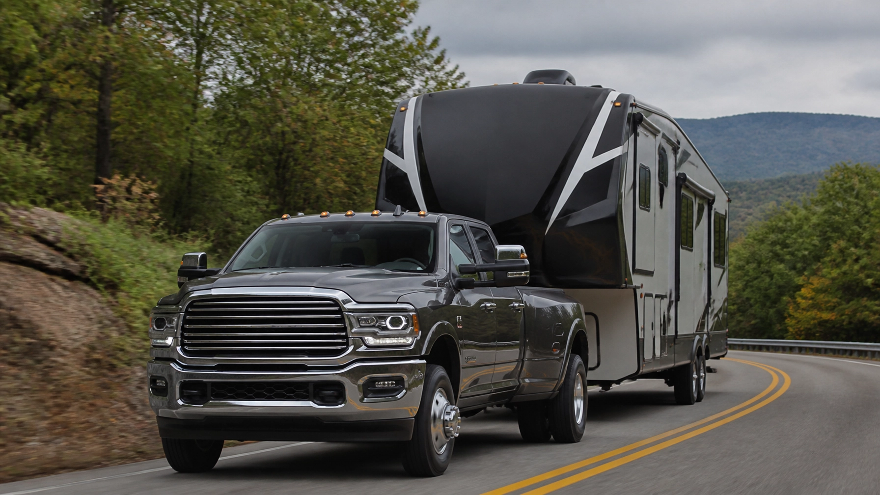 High-performance truck towing a large RV on a scenic mountain road, showcasing power and capability.