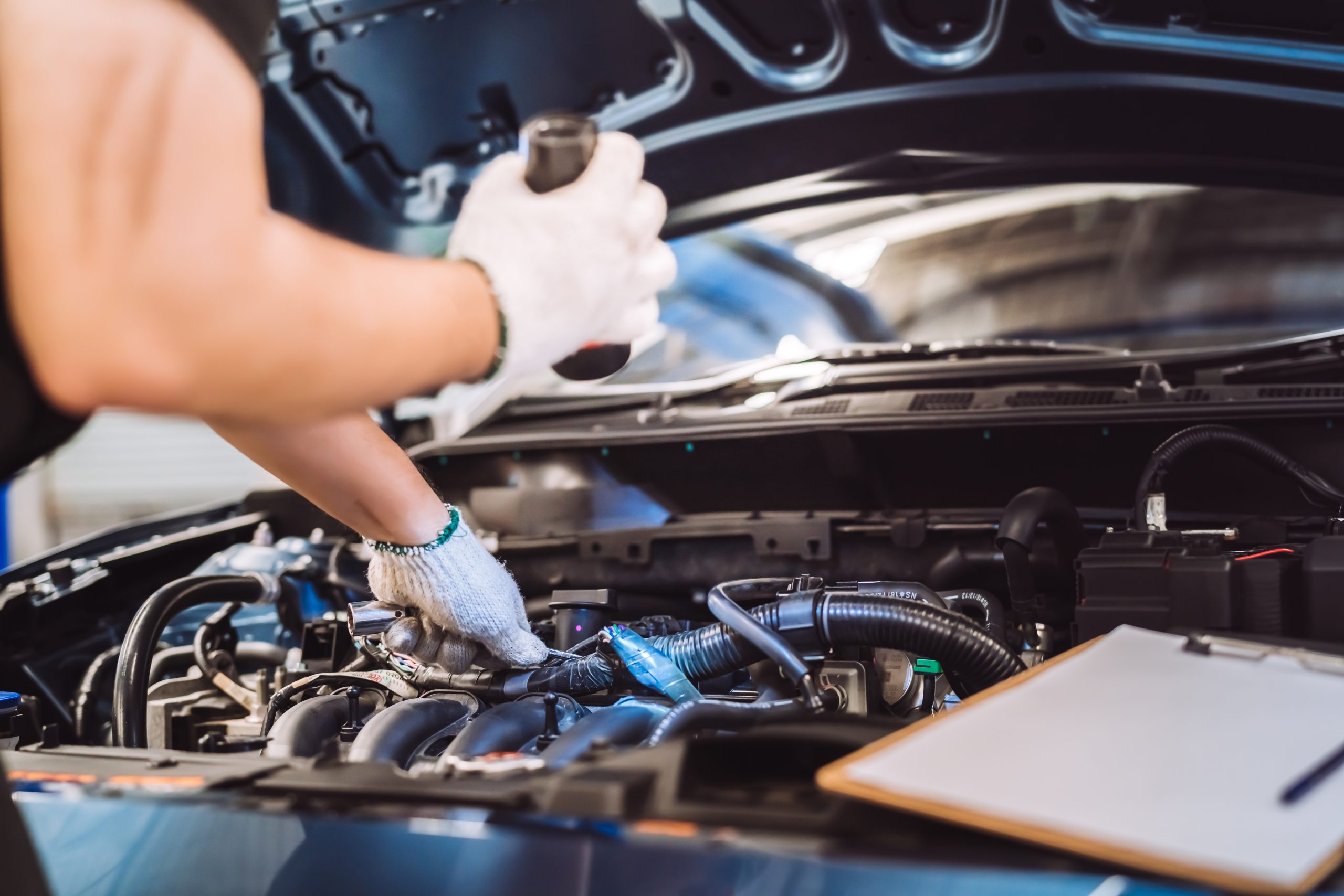 Technician inspecting car engine with open hood at Dirty D’s Performance.