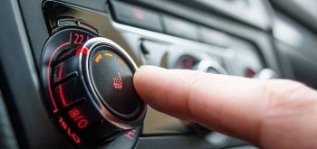Person adjusting car heater temperature on vehicle dashboard.