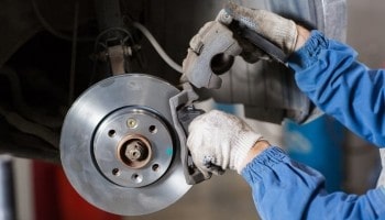 Mechanic inspecting car brake system at Higgins Driscoll’s Auto.