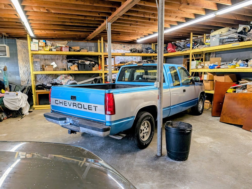 Chevrolet pickup truck inside DrivenMotos auto repair shop, surrounded by tools and car parts.