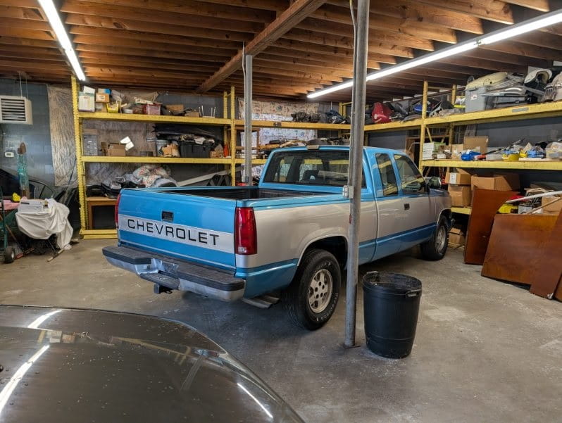 Chevrolet pickup truck inside DrivenMotos auto care clinic, surrounded by tools and shelves.