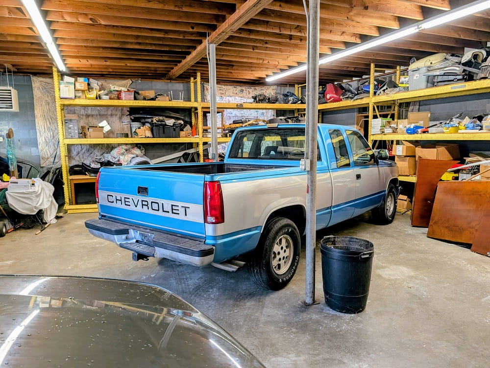 Chevrolet Silverado pickup truck inside DrivenMotos Auto Care Clinic, surrounded by tools and car pa.