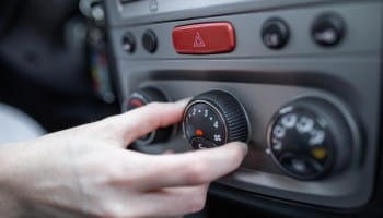Technician adjusting car air conditioning and climate controls.