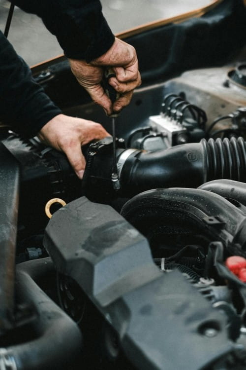 Mechanic working on engine of an American vehicle at DrivenMotos Auto Care Clinic.