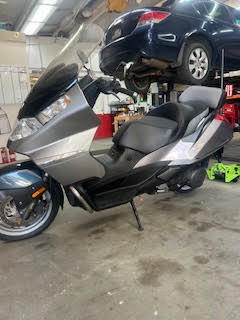 Silver and black scooter inside DrivenMotos auto care workshop.