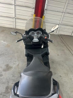 Motorcycle parked inside DrivenMotos Auto Care Clinic with windshield and dashboard visible.