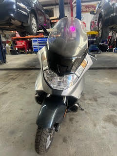 Scooter at DrivenMotos Auto Care Clinic with service bay background.