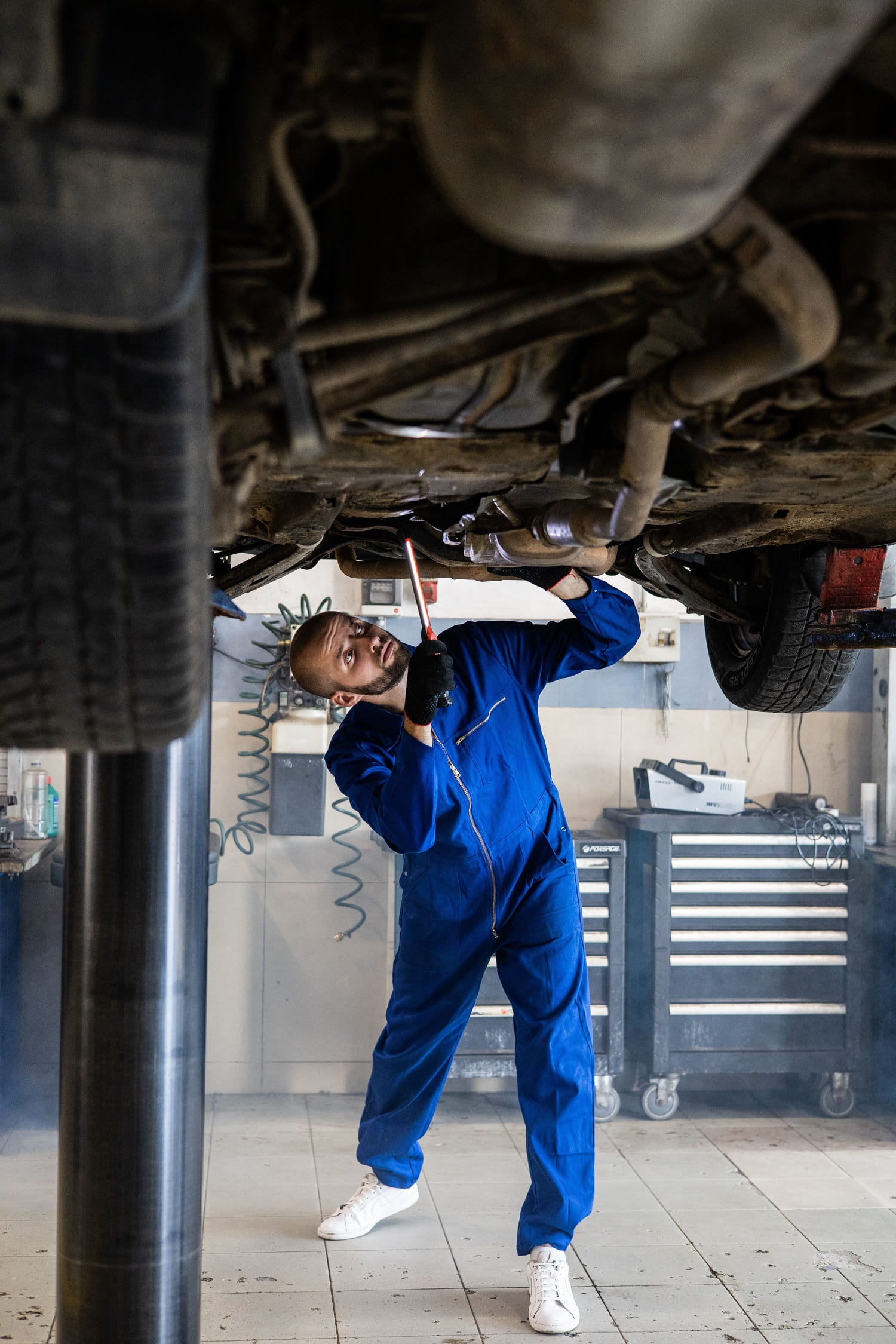 Auto mechanic inspecting underside of vehicle at DrivenMotos.