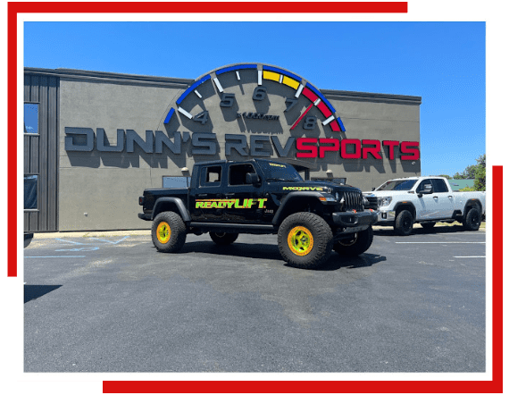 Dunn’s RevSports Exterior Dunn's RevSports building with sports-themed clock and vehicles in parking lot.