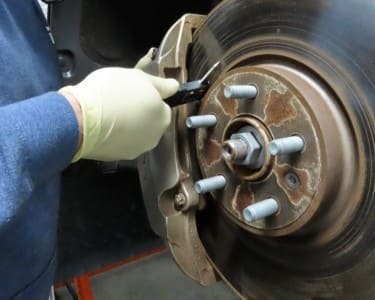 Technician inspecting brake rotor for wear and damage.