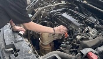 Skilled technician inspecting car engine at E&C Automotive Services.