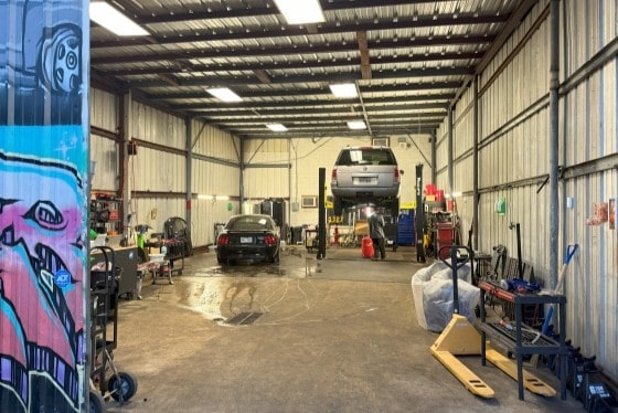 Auto repair shop interior with vehicles, tools, and equipment for vehicle maintenance and repairs.