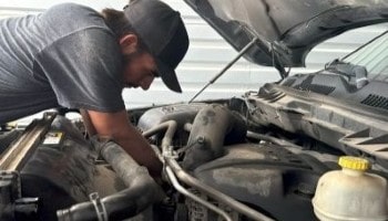 Auto mechanic inspecting vehicle engine at E&C Automotive Services.