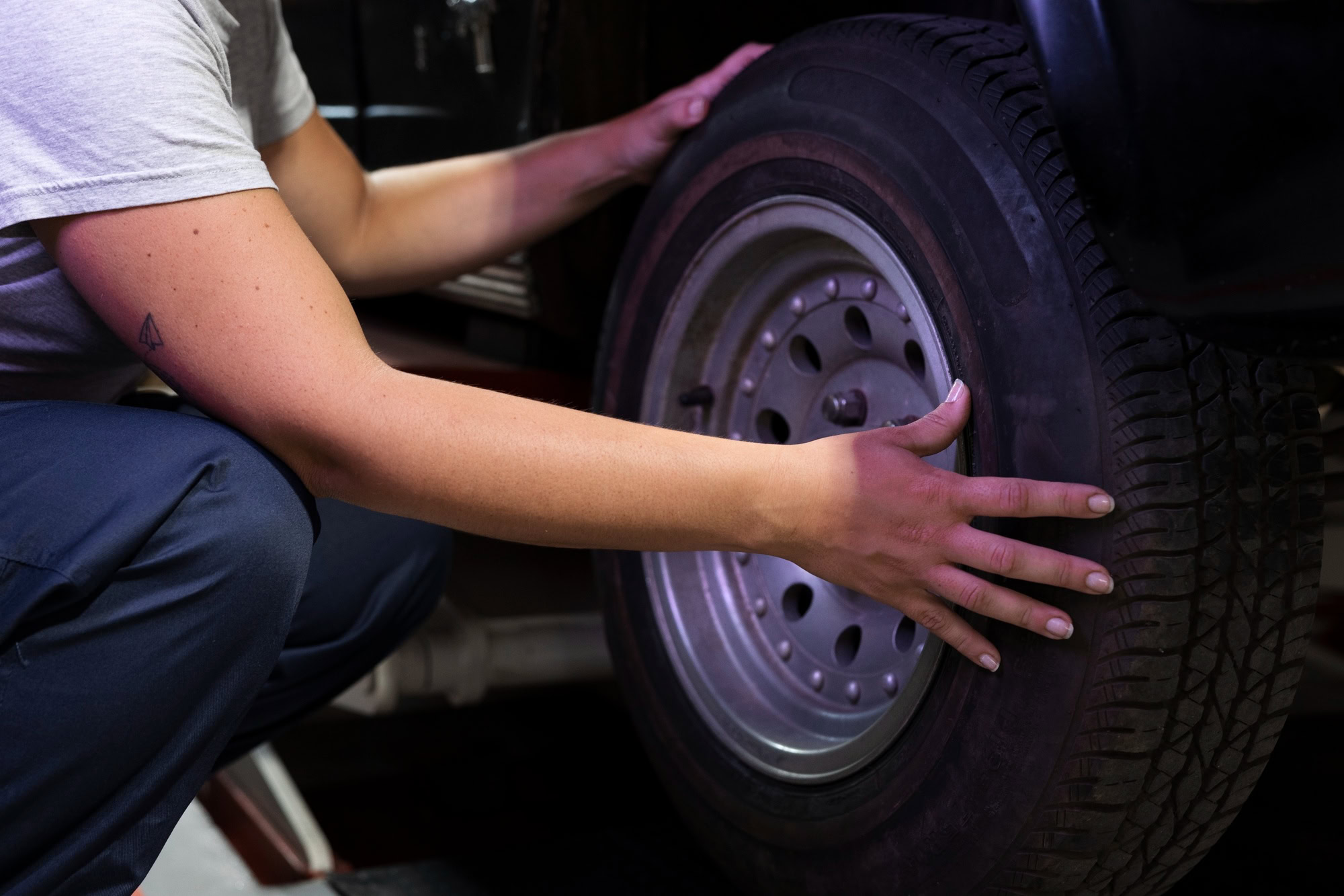 Technician inspecting winter tires for safety on a vehicle at E&C Automotive.