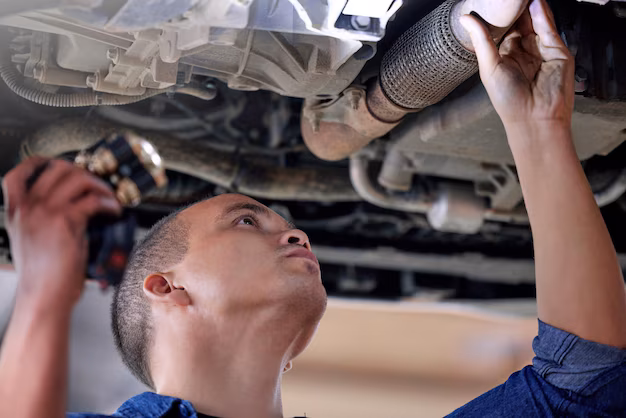Mechanic inspecting undercarriage of car for faults