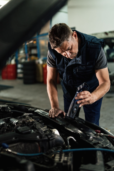 Skilled mechanic inspecting car engine at Ed's Auto Repair shop.