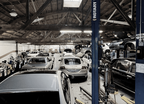Auto repair shop with multiple cars and equipment inside a spacious garage.