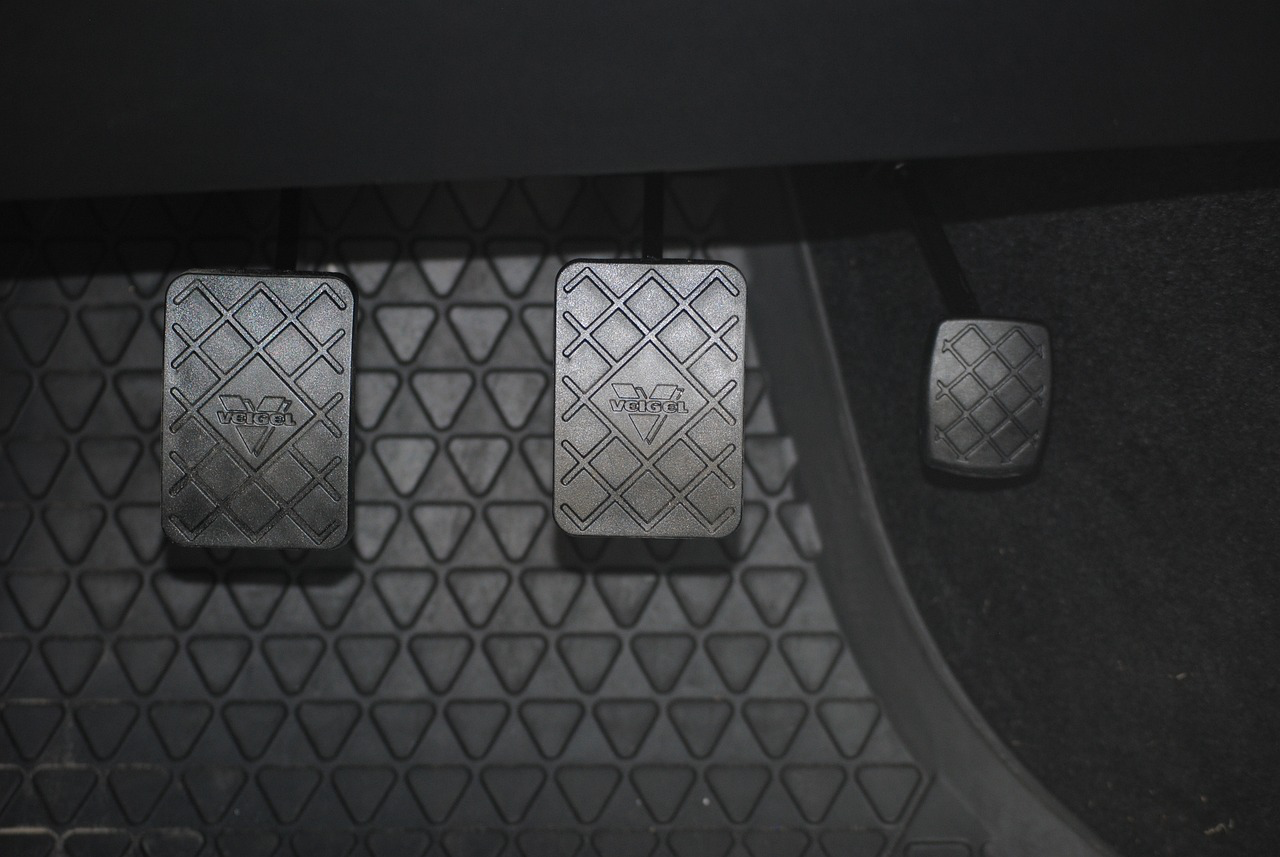 Clutch pedal and floor mat in a vehicle, showing signs of wear.