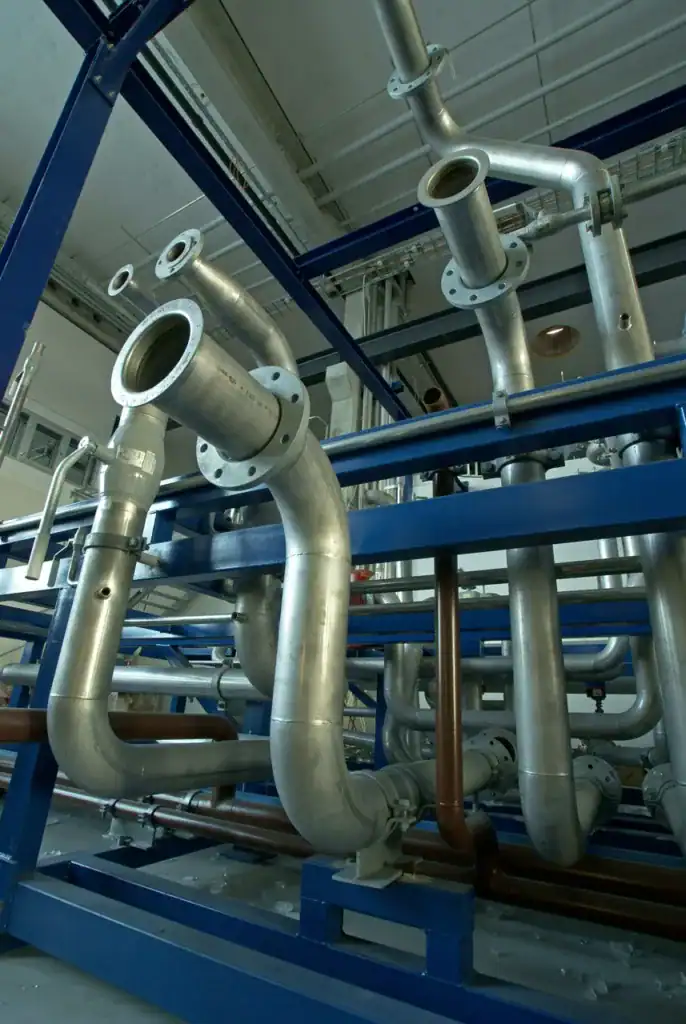 Complex network of stainless steel pipes and valves in an industrial setting.