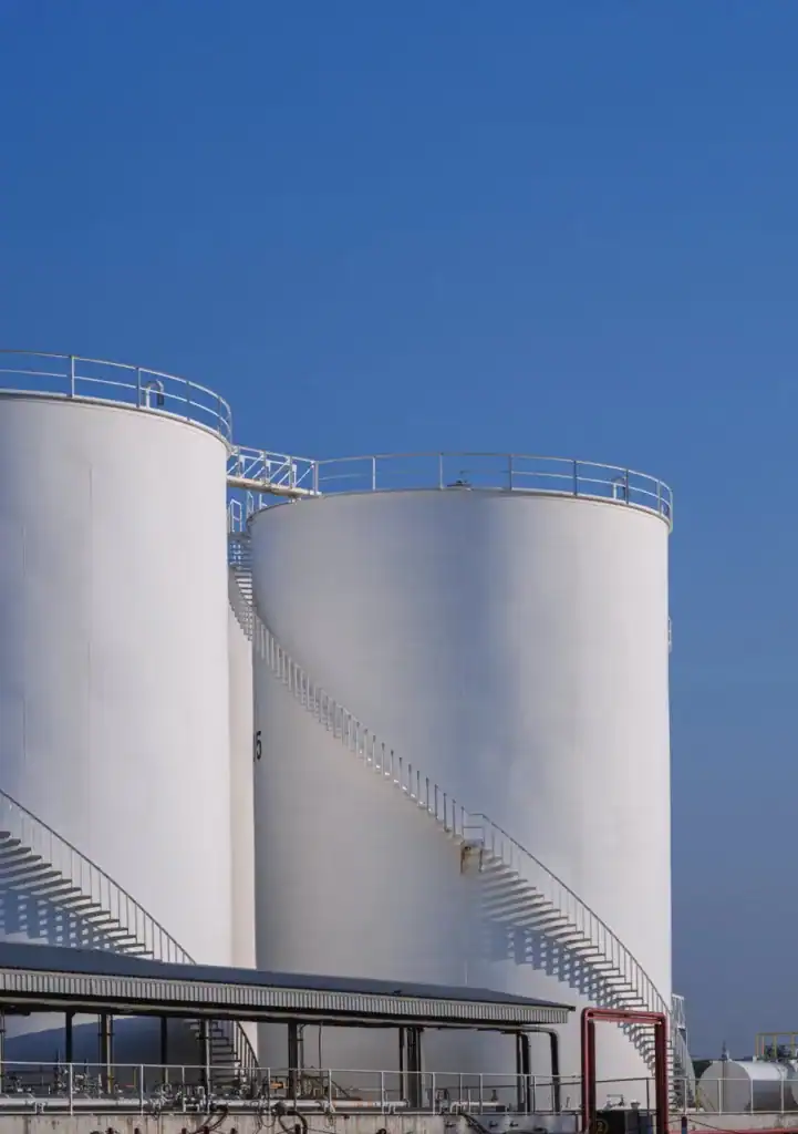 Oil storage tanks at an industrial facility under a clear blue sky.