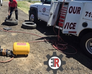 Tire repair service with technician and equipment on roadside.