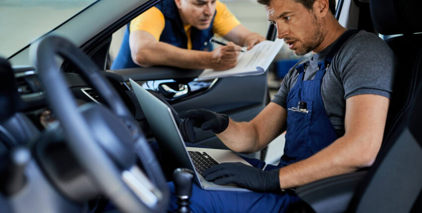 Auto technician inspecting a vehicle's engine in the workshop.