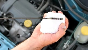 Auto maintenance technician checking engine oil level.