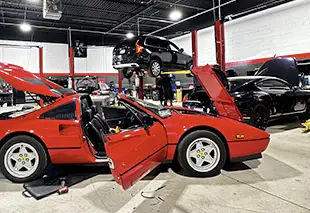Red classic sports car with open doors in an automotive workshop.