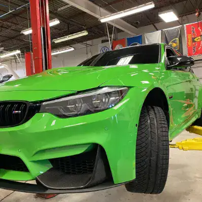 Bright green sports car inside an automotive workshop.