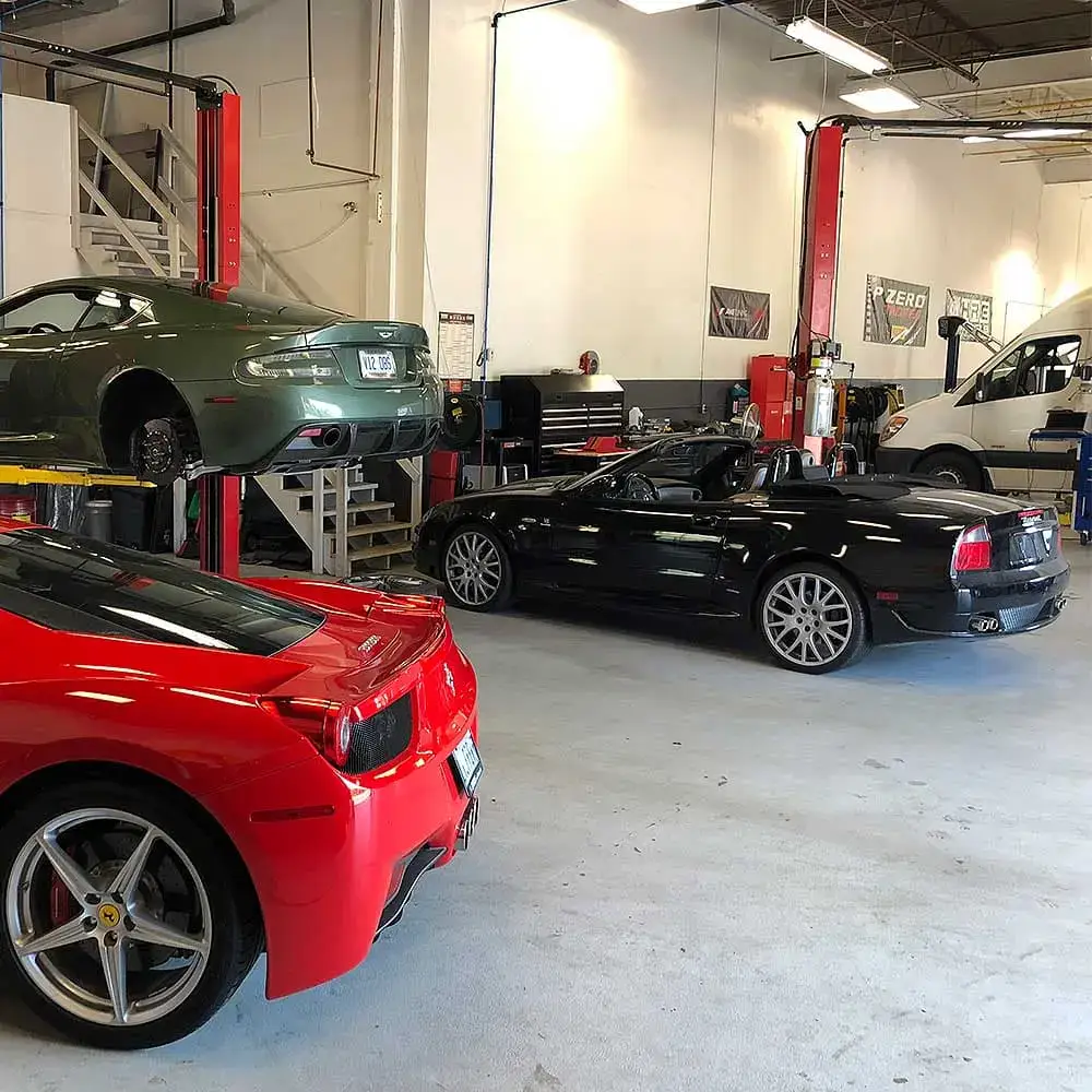 Inside a European automotive repair shop with multiple luxury cars being serviced.