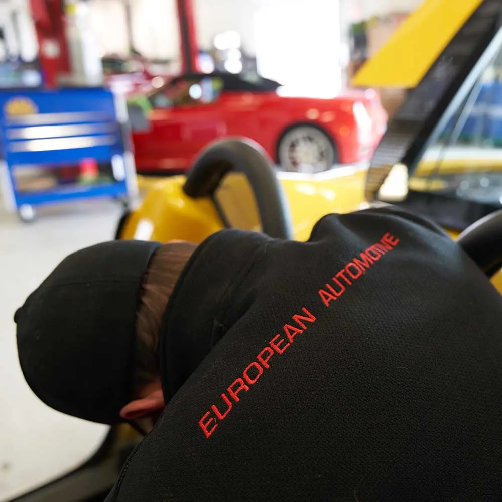 Technician working on a vehicle in a European automotive repair shop.