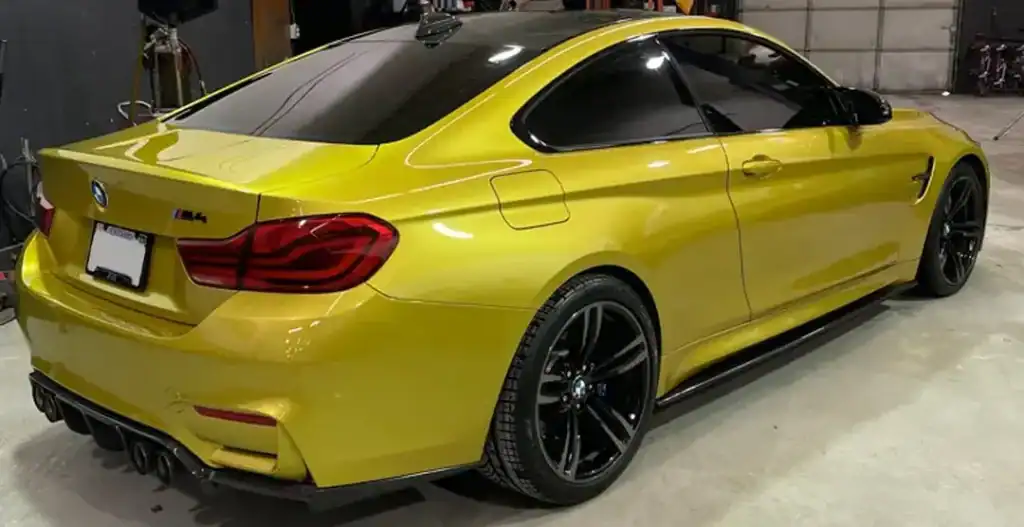 Yellow BMW M4 coupe with black wheels in a garage setting.