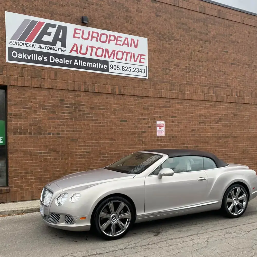 Silver luxury convertible car parked outside European Automotive dealership.