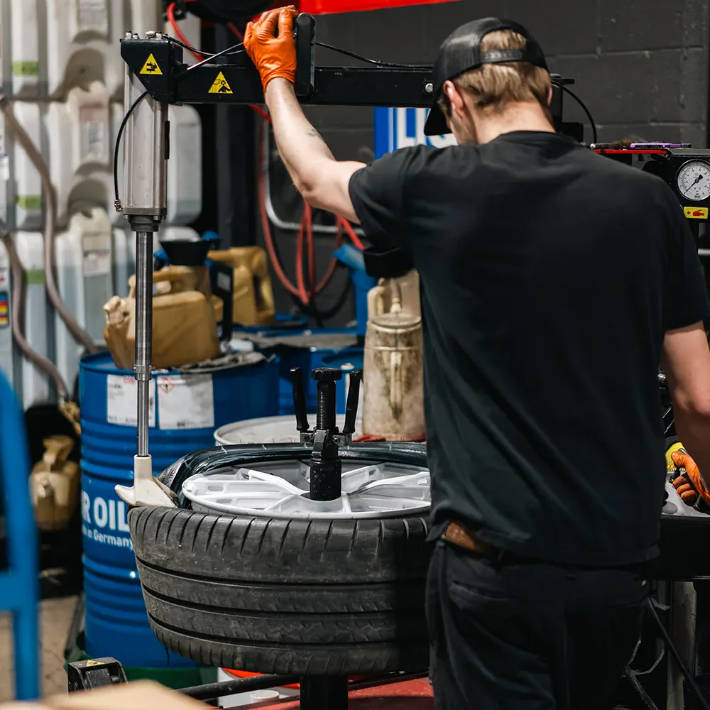 Technician repairing tire at European Automotive workshop.