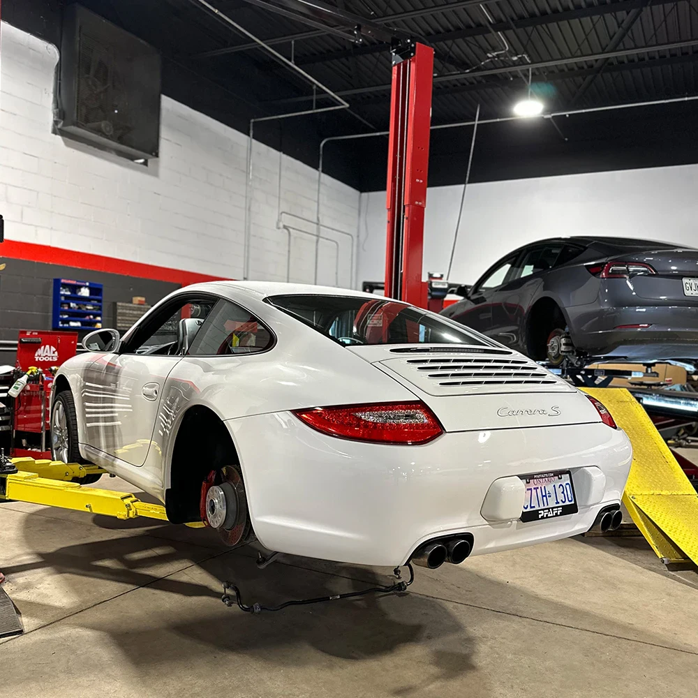 White Porsche 911 on lift at European automotive repair shop.