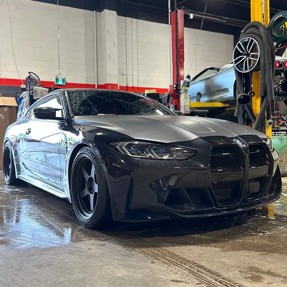 Black sports car in a garage with automotive equipment.