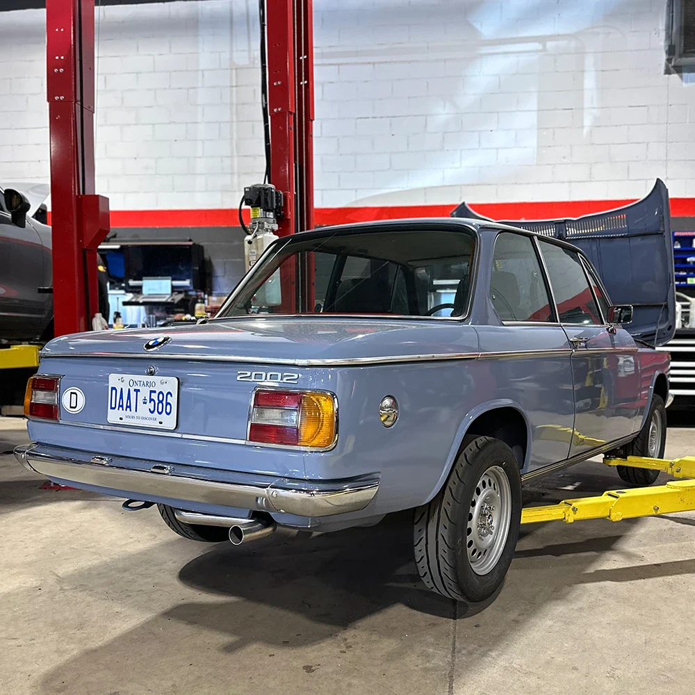Vintage 2002 European Automotive car in workshop with open trunk.