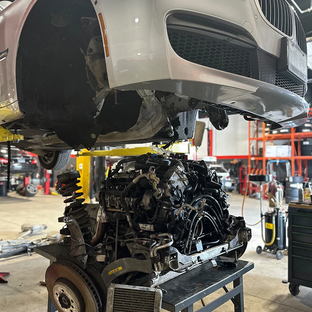 Underbody view of a car with engine removed in a professional workshop.