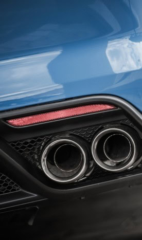 Close-up of dual exhaust pipes on a blue European sports car.