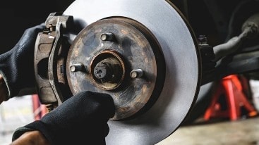 Technician inspecting a vehicle's brake disc for safety and performance.