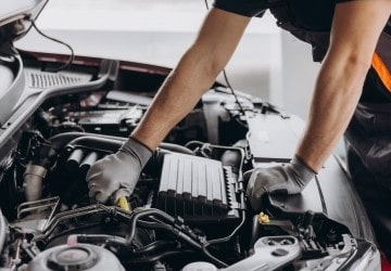 Auto mechanic inspecting car engine during service.