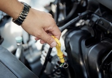 Technician checking engine oil in a car engine at Express Tire & Auto Service.