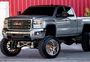 GMC pickup truck with custom rims, lifted suspension, and off-road tires at Express Tire And Auto Se.
