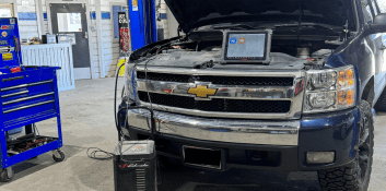 Auto repair technician diagnosing vehicle engine issues with diagnostic tools.