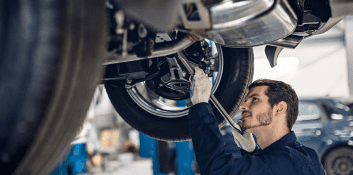 Skilled mechanic inspecting car brake system during repair.